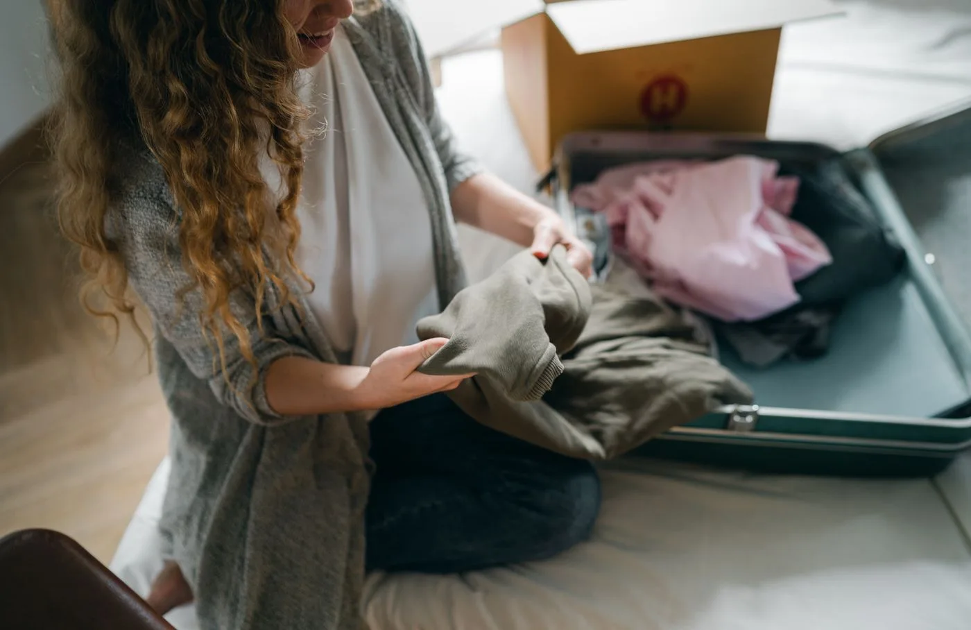A woman arranging clothes in a suitcase on a bed