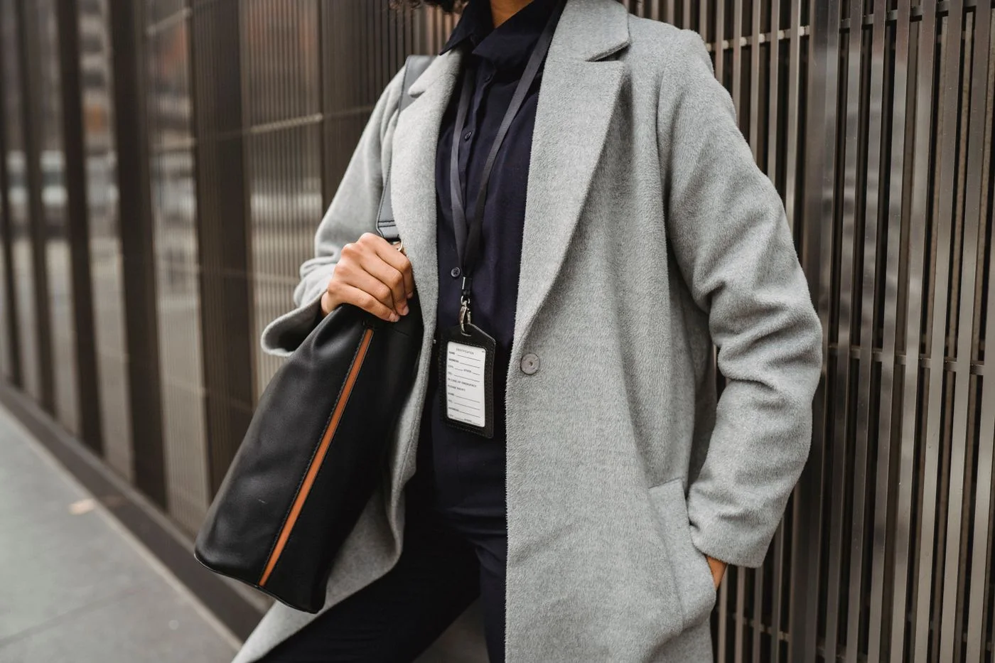 A woman in a grey coat carrying a dark shoulder bag.