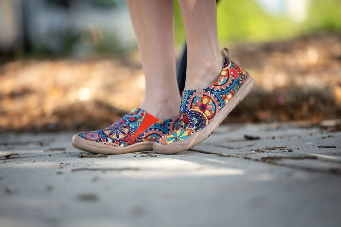 Colorfully patterned lace-up shoes above a paved surface.