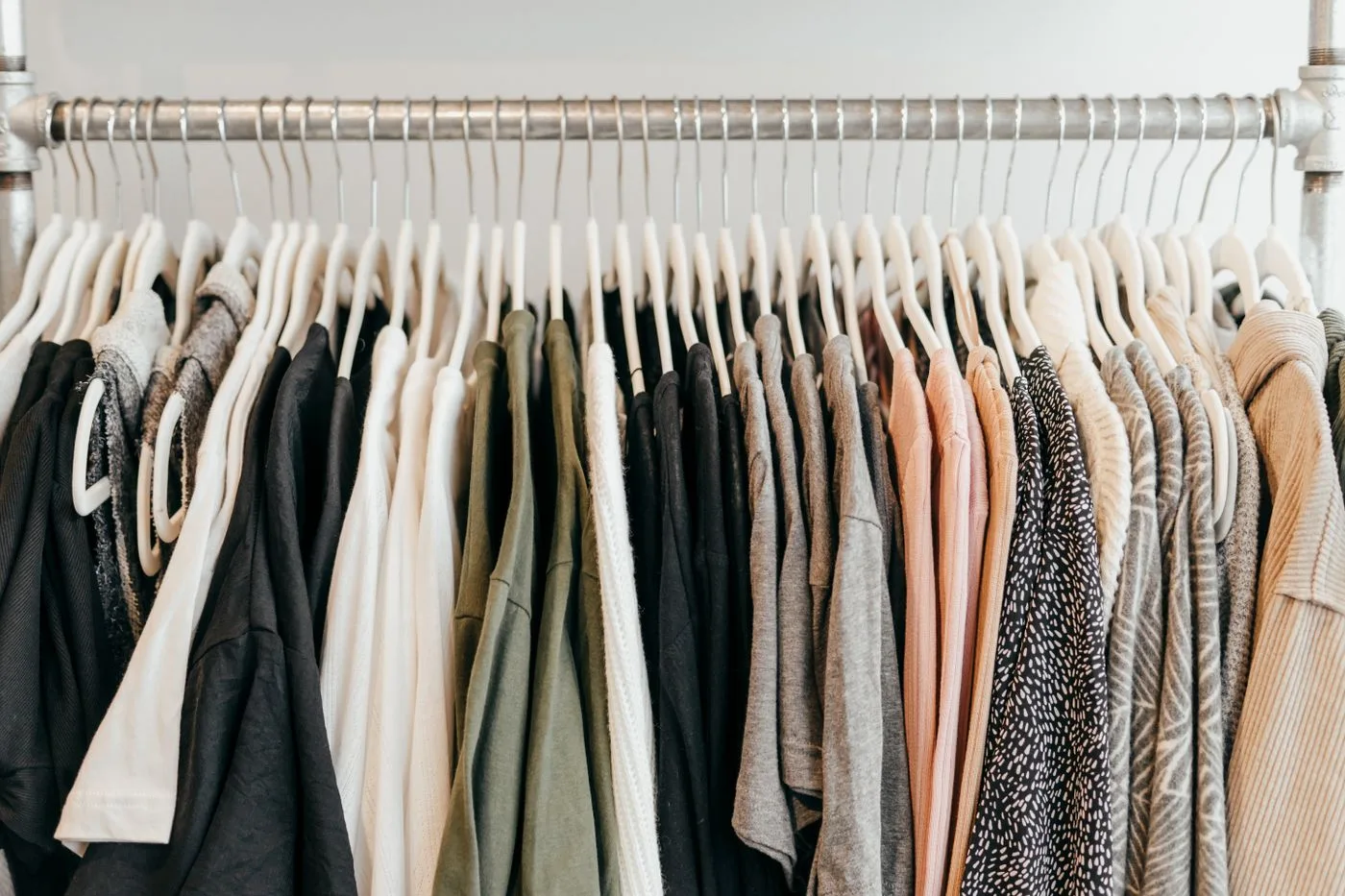 A long rail of pale and dark garments on hangers.