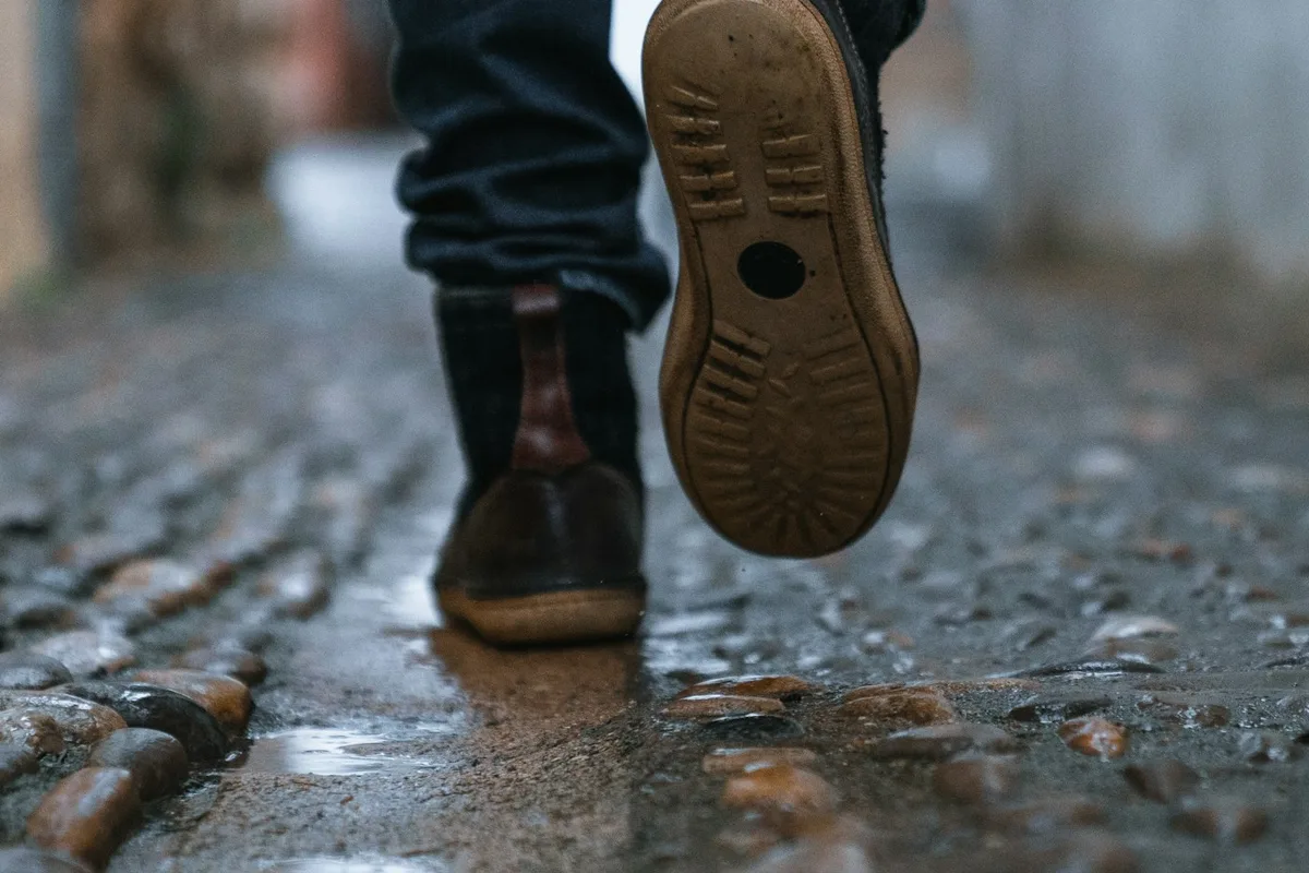 Close-up of a person walking across pavement in everyday shoes