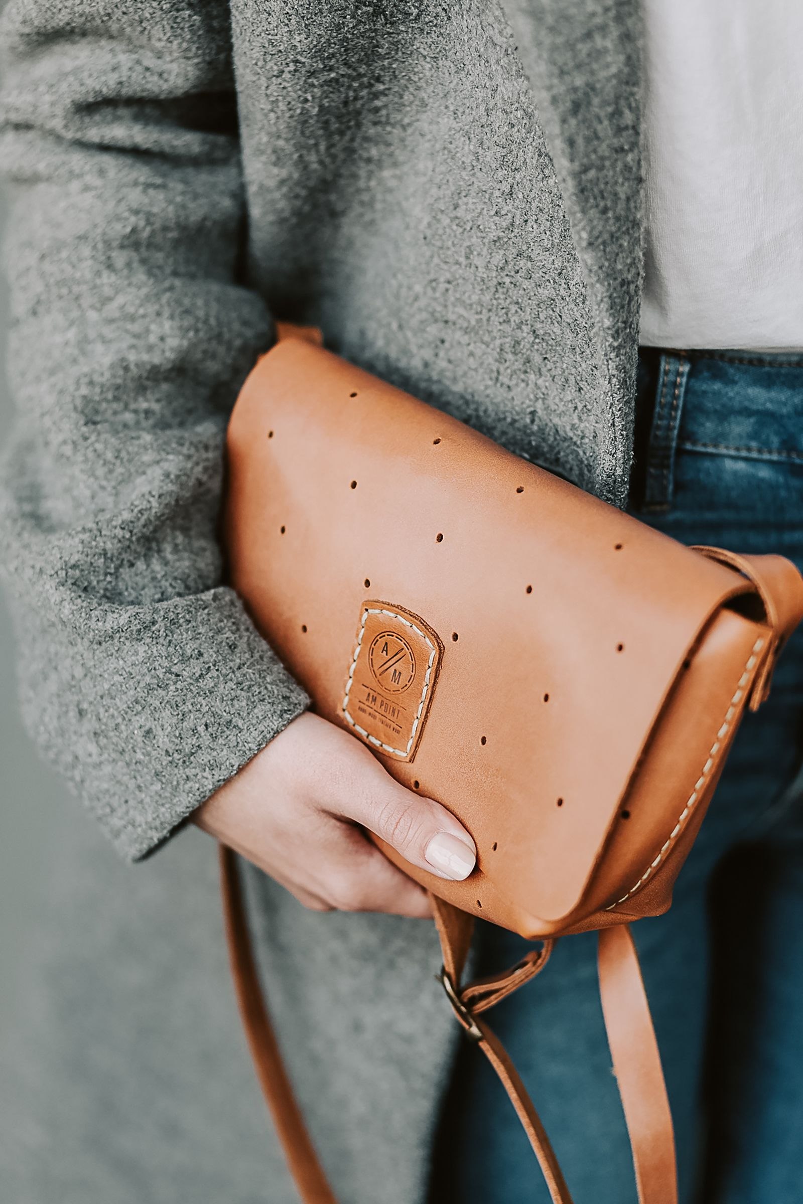 Woman wearing a gray coat and holding a tan handbag