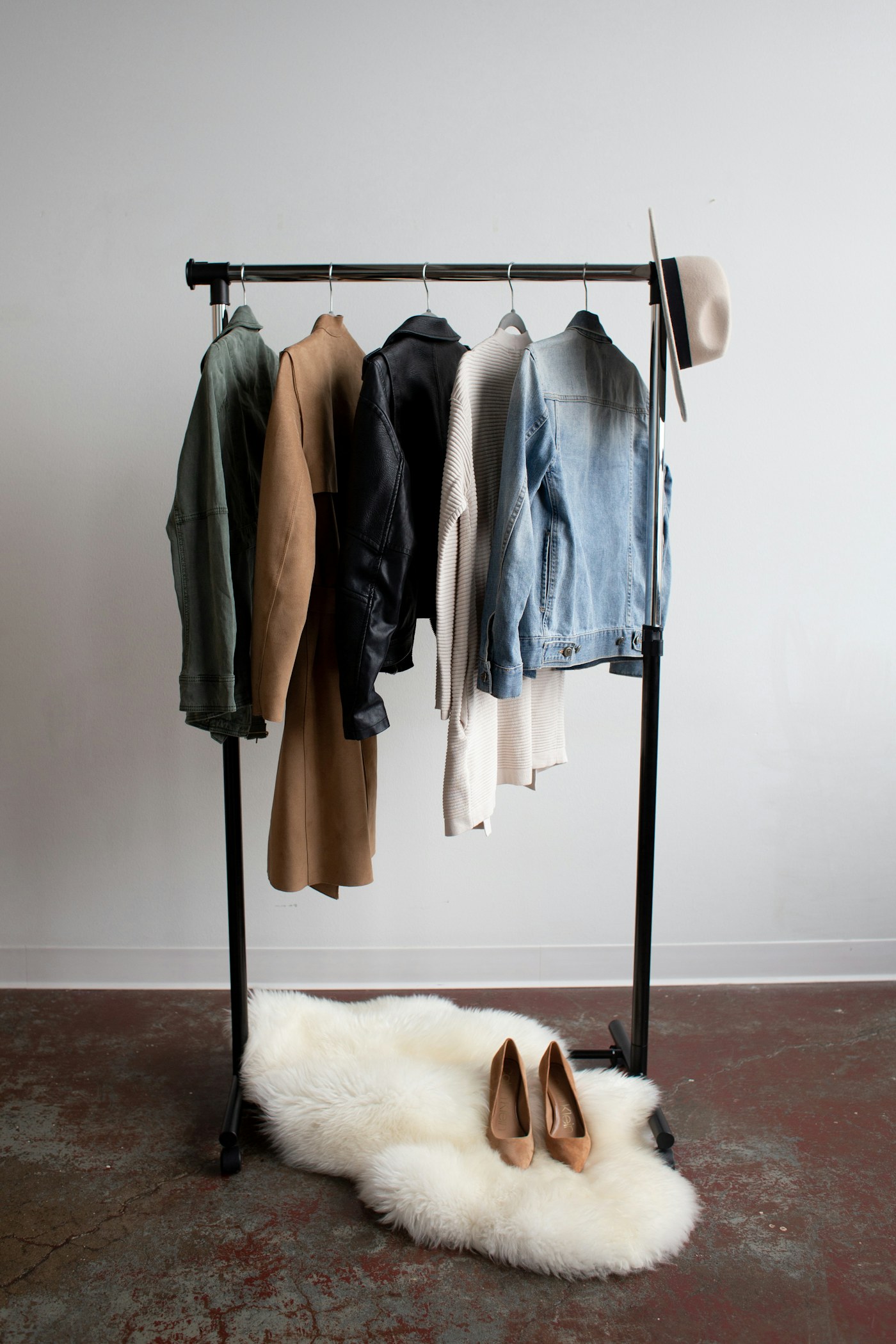Coats and other garments hanging on a dark freestanding rail.