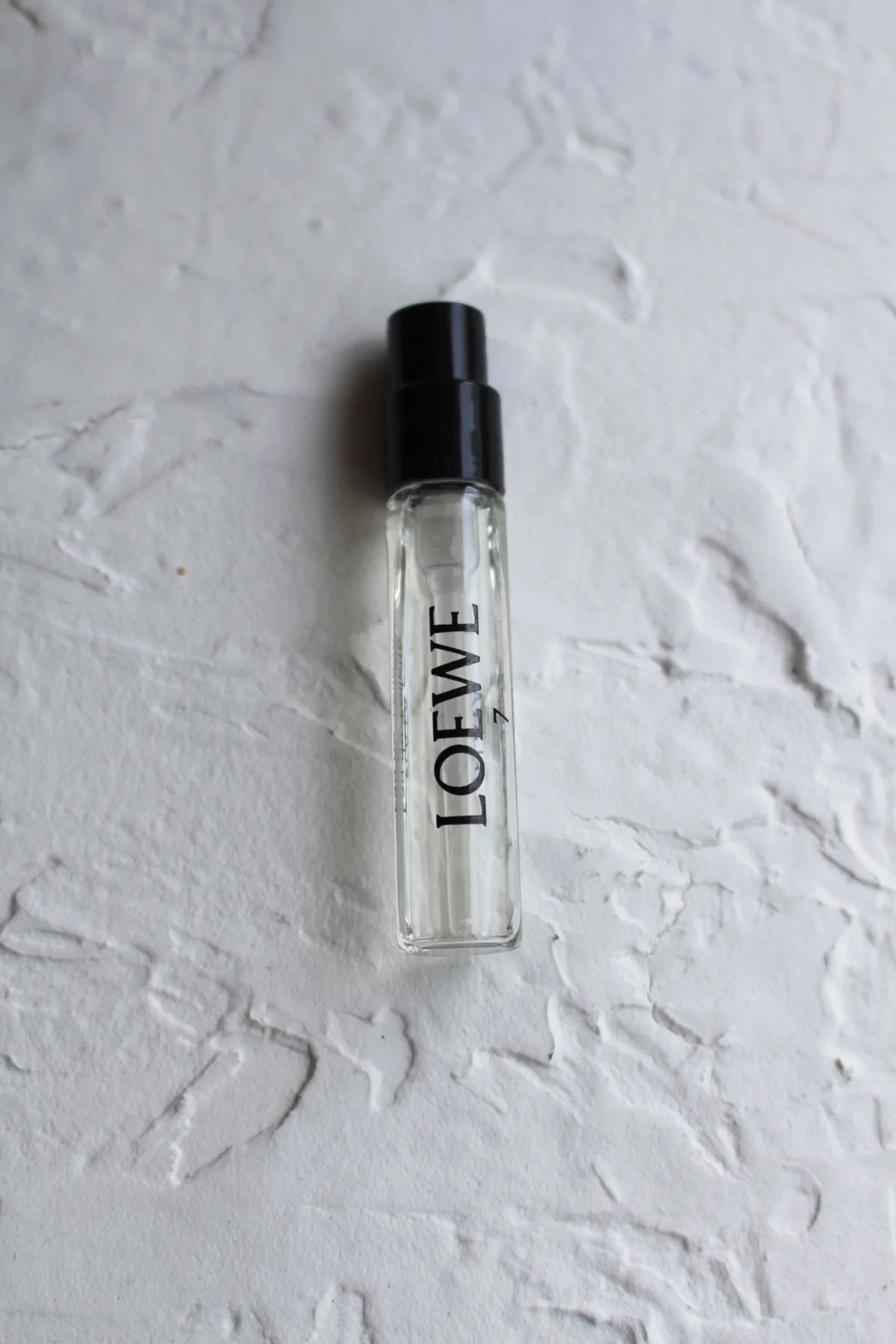 A labelled fragrance sample vial on a white surface.