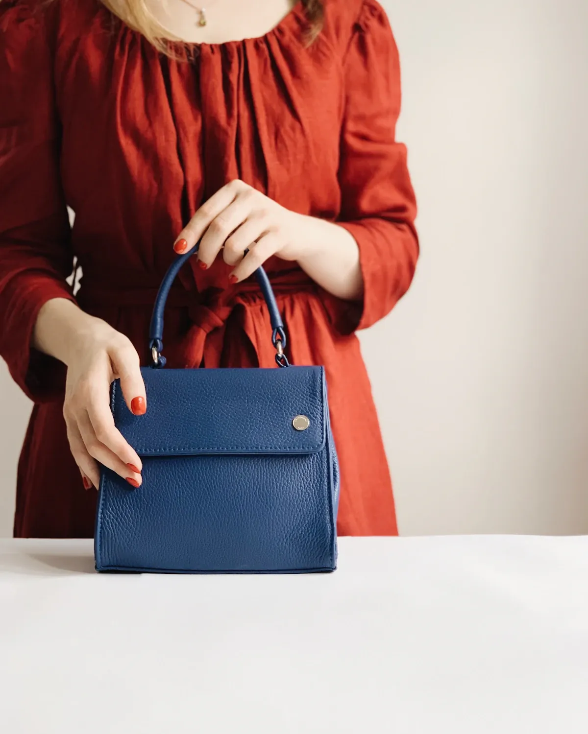 A woman holding a blue leather handbag