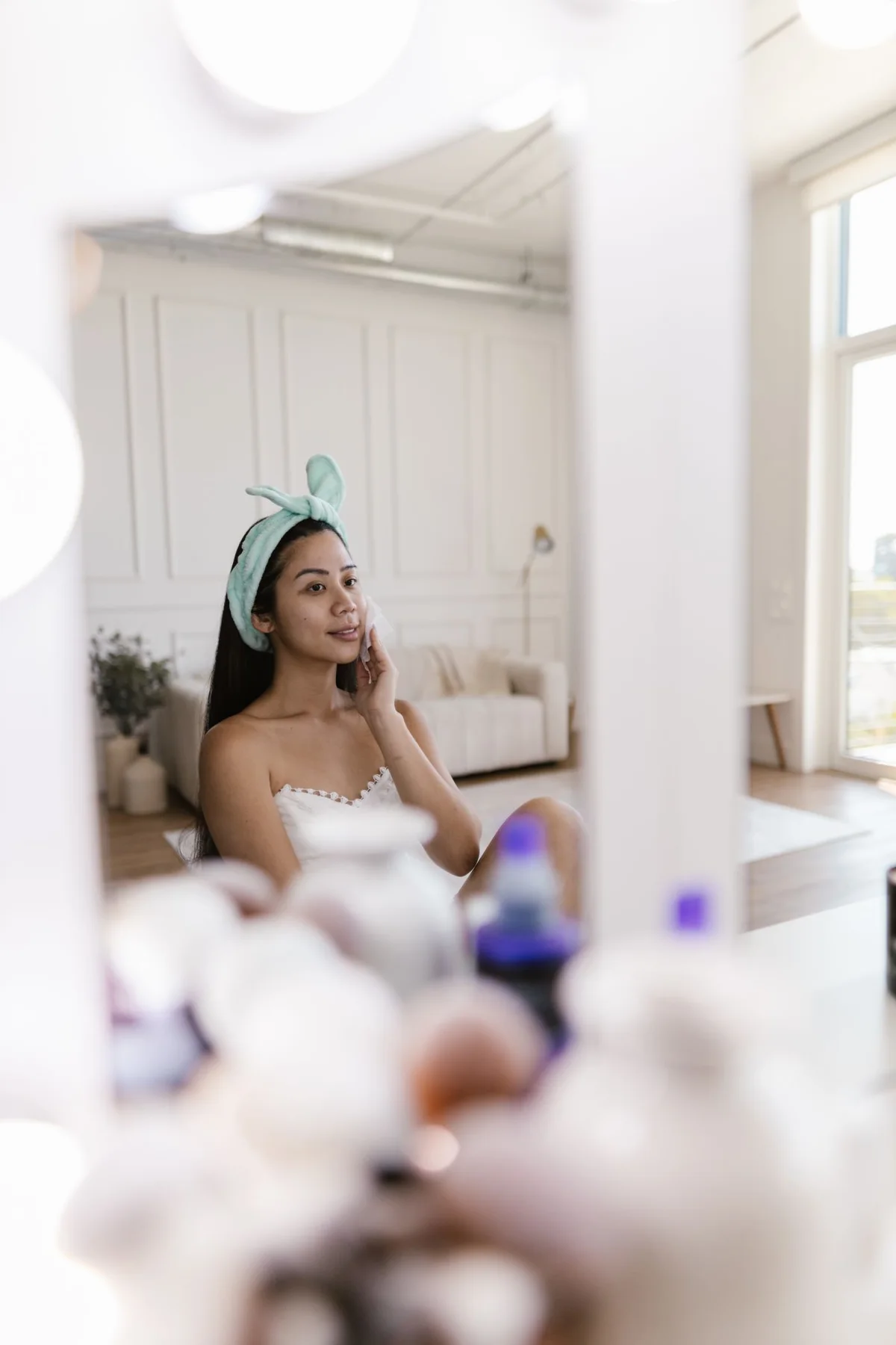 A woman wearing a soft headband while looking in a mirror.