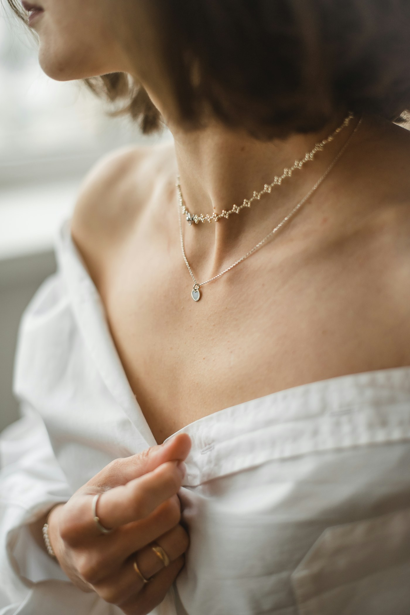 Layered gold necklaces worn with a white blouse