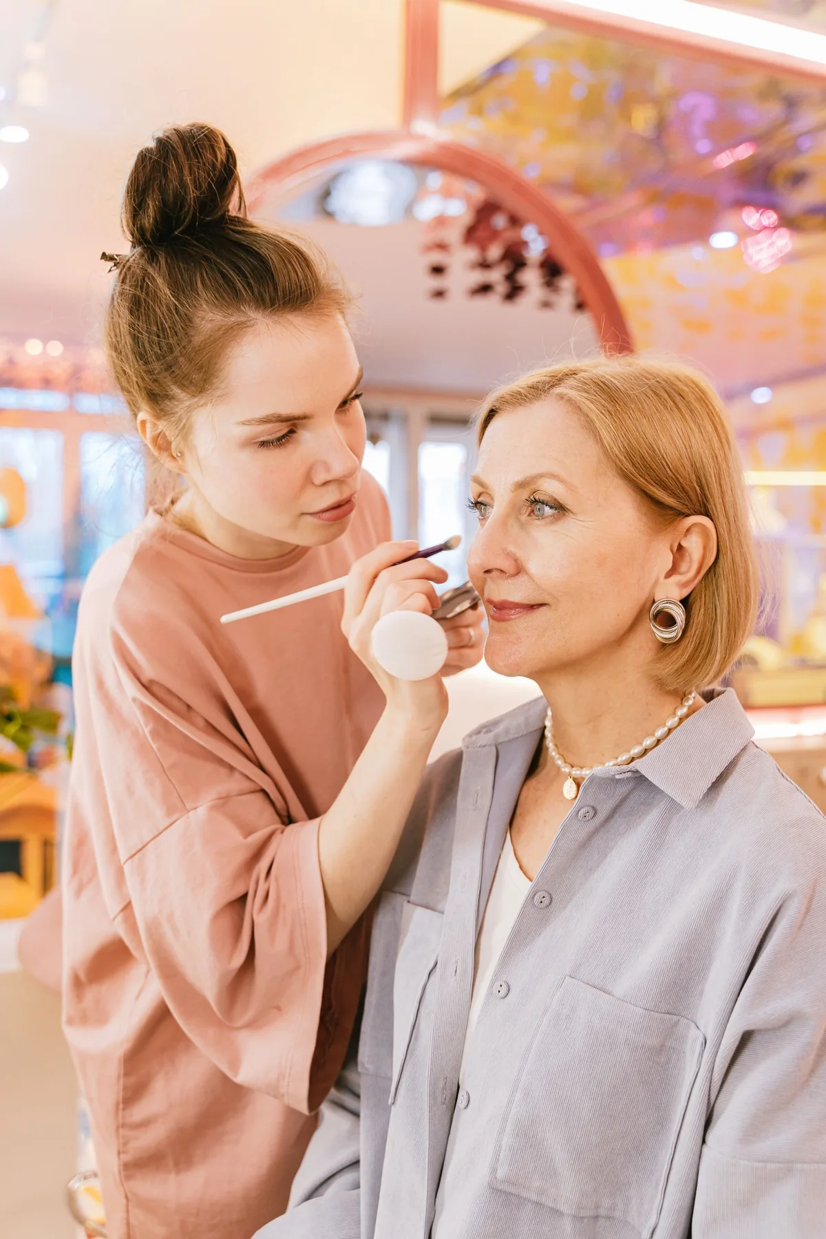 A makeup artist applying makeup to a seated client.