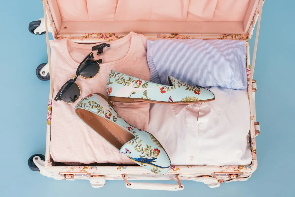 Clothing and a pair of shoes organised inside an open suitcase