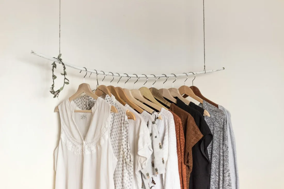 Pale and neutral-coloured garments arranged on wooden hangers.