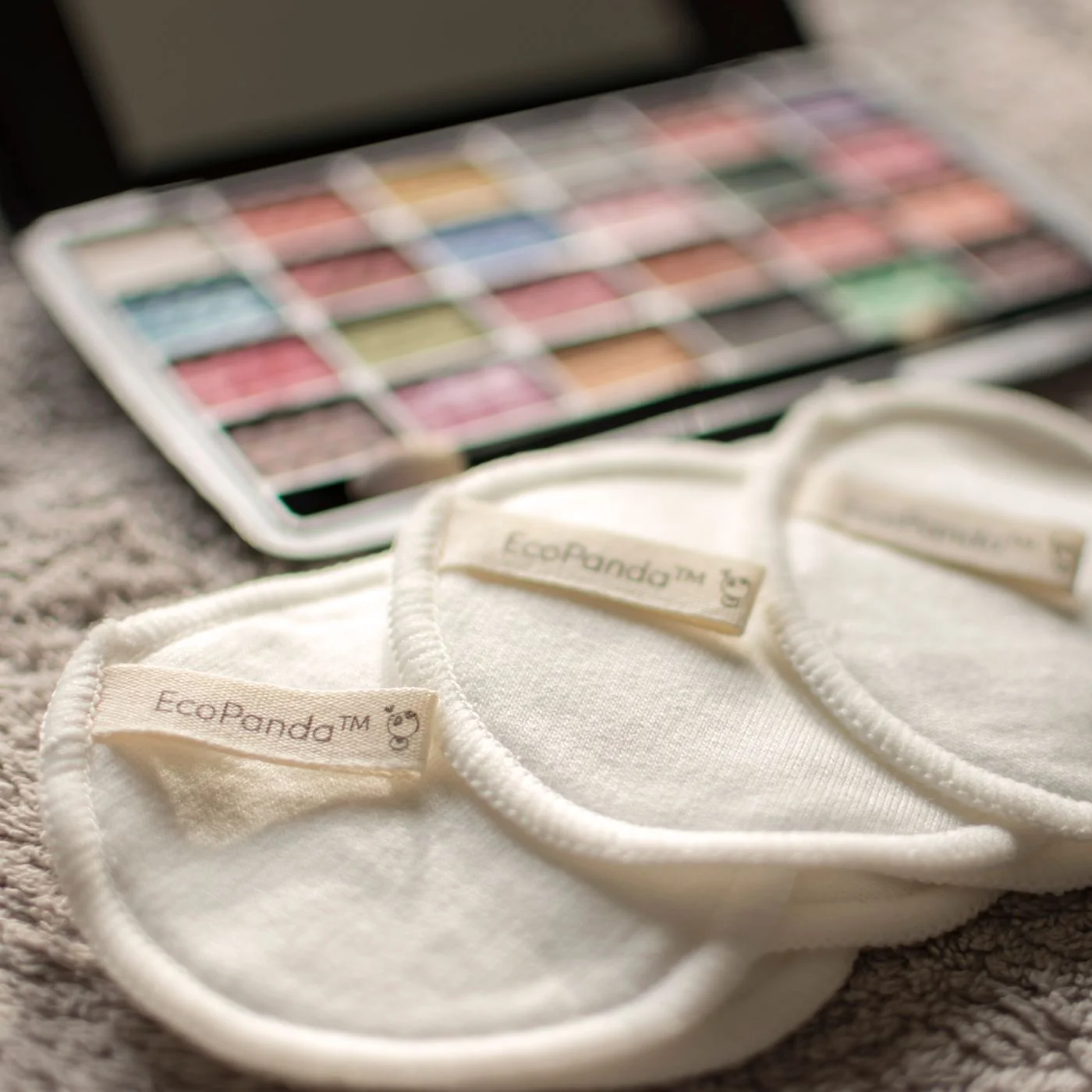 Reusable cotton pads beside an open makeup palette.